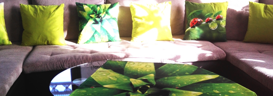 Zielona poduszka z nadrukiem na szarej sofie